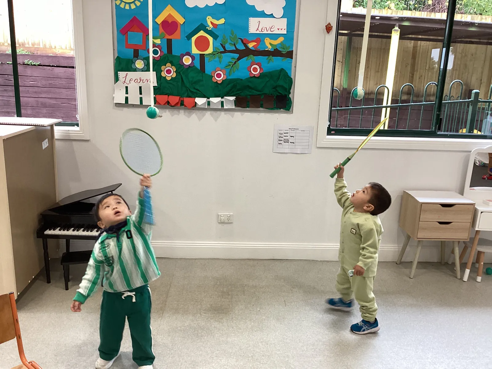 Toddlers exploring a hands-on wall activity together with curiosity