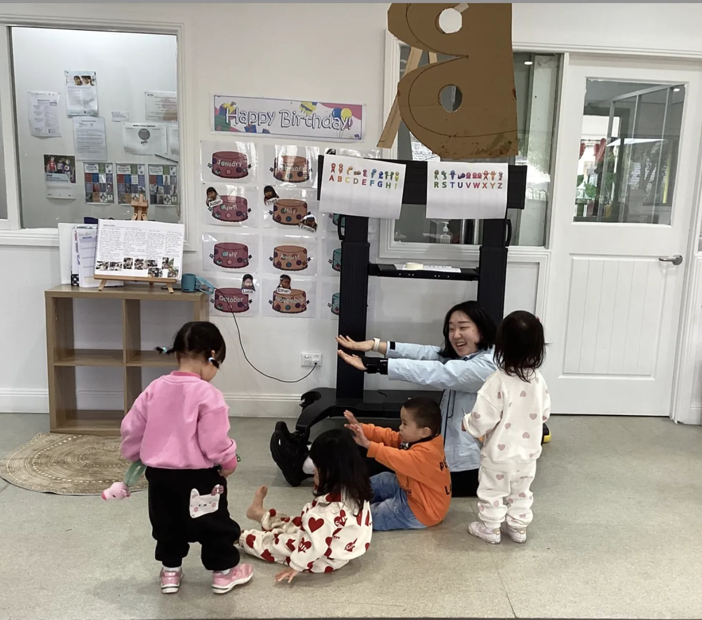 Educator playing joyfully with toddlers in the Little Sharkies learning room
