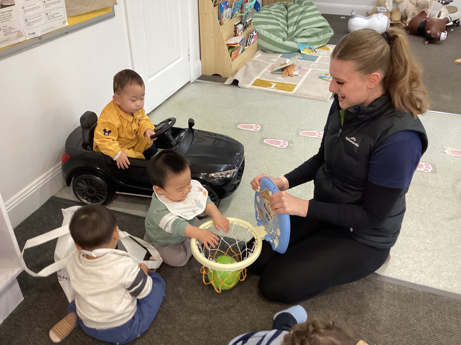 An educator playing a ball game with toddlers in the nursery room